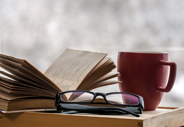 Reading an old book with glasses at home on a cold winter evening. Reading a book at home with coffee