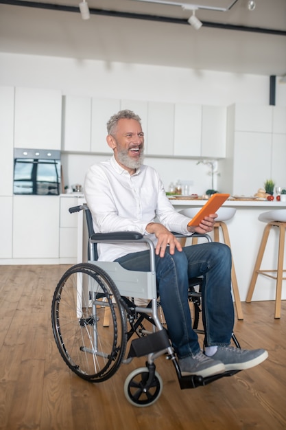 Reading online. Gray-haired handicapped man with a tablet in hands