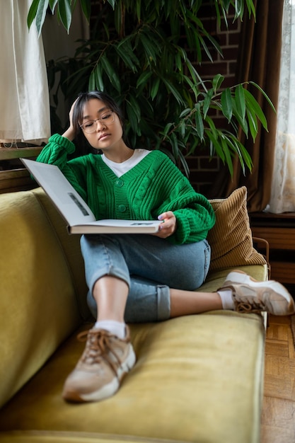 Reading Young asian girl with a big book sitting on the sofa