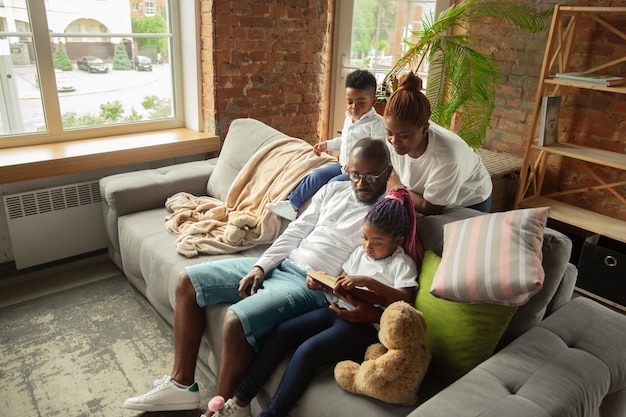 Reading Young and cheerful african family during quarantine insulation spending time