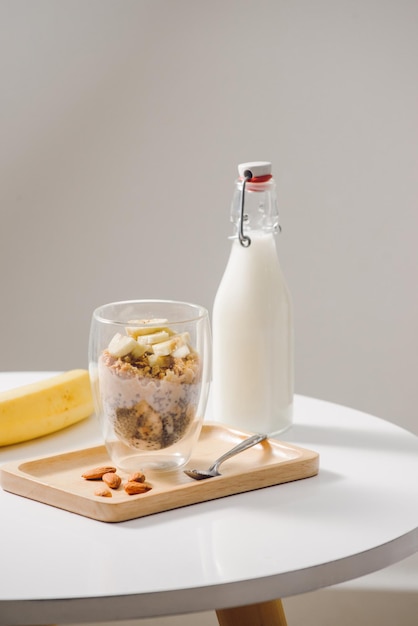 Ready to eat healthy an nutritious breakfast - granola with almonds, chia seeds, banana and kiwi fruits and berries and a jar with milk nearby