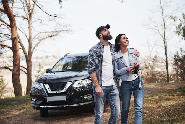 Ready for the new directions. Embracing and enjoying the nature. Couple have arrived to the forest on their brand new black car