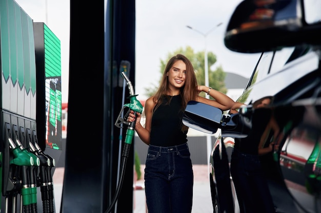 Ready to refill the automobile A young woman at a gas station with her car