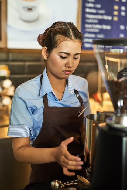 Ready to serve up your caffeine kick Shot of a focused young barista working behind the cash register in a coffee shop