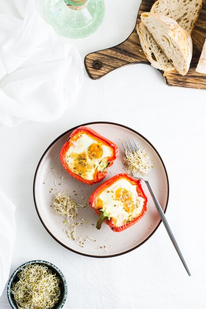 Readytoeat bell pepper halves baked with egg and microgreens on a plate on the table Healthy organic diet Top and vertical view