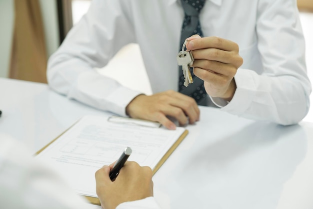 Real estate agent giving house keys to client after signing home loan contract