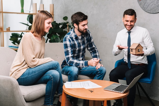 Real estate agent showing toy house to couple