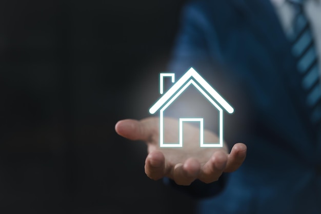 Real estate concept a businessman holding an icon of a house house available Property insurance and security concept Man protective gesture and house symbol