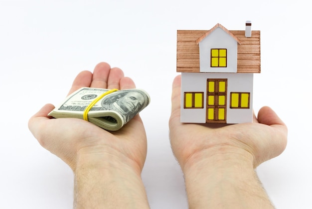 Real estate concept from figurine house and money in hands