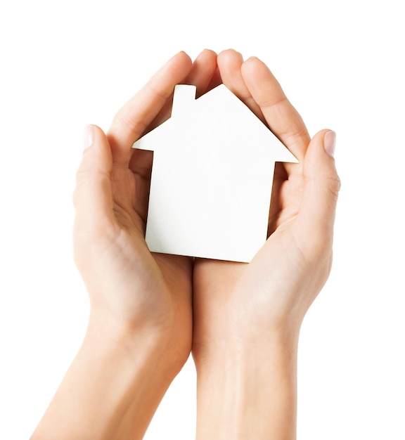 real estate and family home concept - closeup picture of female hands holding white blank paper house