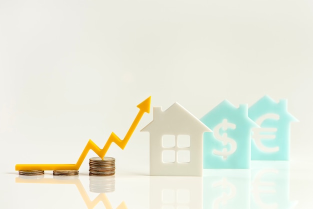 Real estate market, graph, up arrow. House model and a stack of coins. The concept of inflation, economic growth, the price of insurance services. Copy space