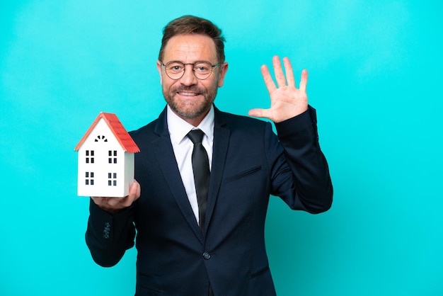 Real estate middle age agent man isolated on blue background counting five with fingers