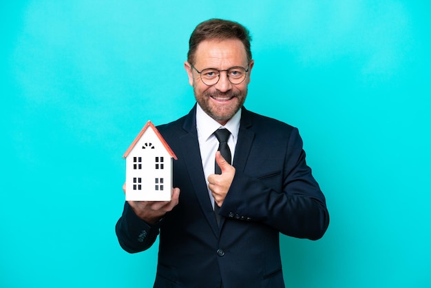 Real estate middle age agent man isolated on blue background giving a thumbs up gesture