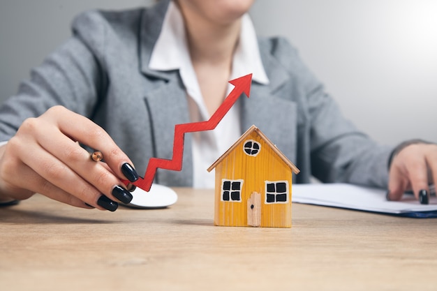 Real estate, woman holding house model with arrow