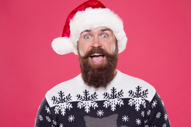 Photo real feelings christmas time happy bearded man santa hat brutal hipster favorite sweater red background winter holiday fun happy face mustache portrait of santa man with beard new year party