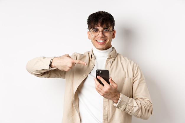 Real people. Handsome young man in glasses pointing finger at smartphone screen