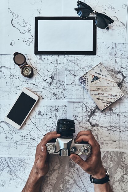 real traveler. close up top view of man holding photo camera with smart phone, sunglasses