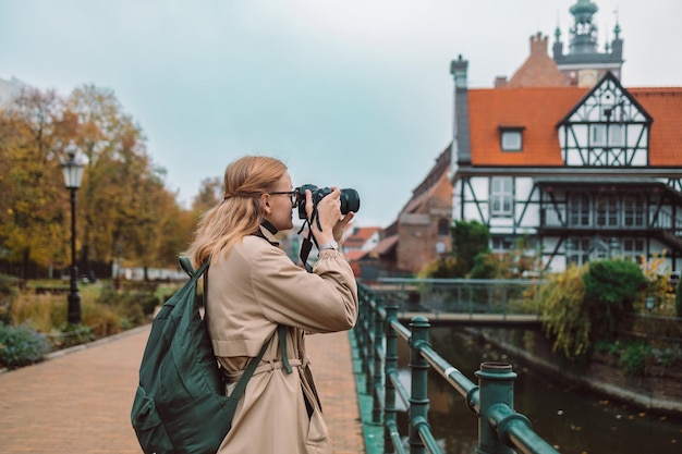 Real view of young european lady tourist in hat makes photo or video at city of gdansk poland high q