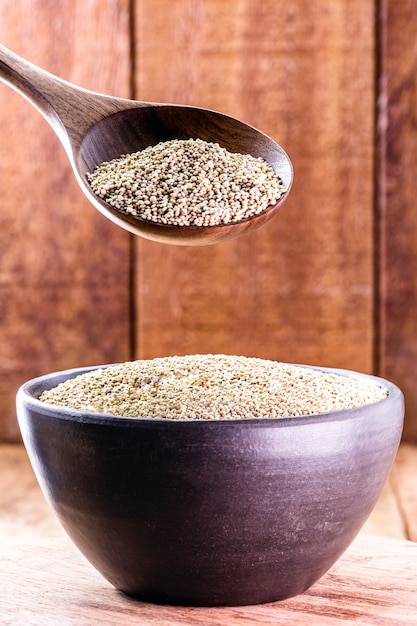 Real white quinoa in a natural wooden spoon with clay bowl. Top view