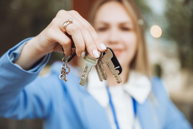 A realtor woman holds the key to an apartment in a new house the owner of the property makes a sale buys the concept of a real estate transaction closeup