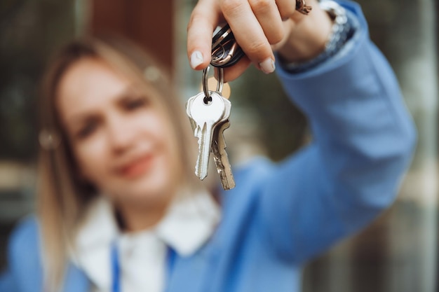 A realtor woman holds the key to an apartment in a new house the owner of the property makes a sale buys the concept of a real estate transaction closeup