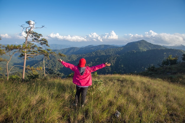 Rear of happy woman stand on top mountain looking view with mist and cloud at Doi Langka Luang, Chiang Rai province. soft focus.