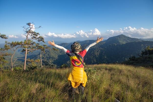 Rear of happy woman stand on top mountain looking view with mist and cloud.