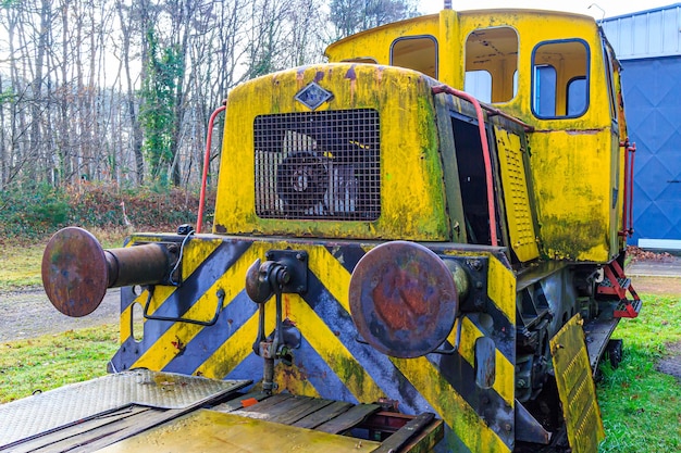 Photo rear part of old yellow ruined train control cabin on disused tracks at old station coupling stops and loading flat platform rusty and corroded metal cloudy autumn day in as limburg belgium