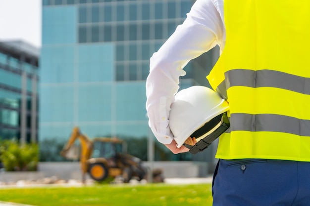 Rear view of architect holding a helmet observing remodeling works