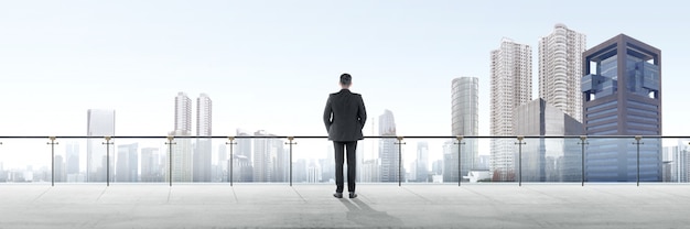 Rear view of asian businessman standing on modern terrace and looking at view