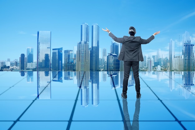 Rear view of Asian businessman standing with raised hand on the rooftop