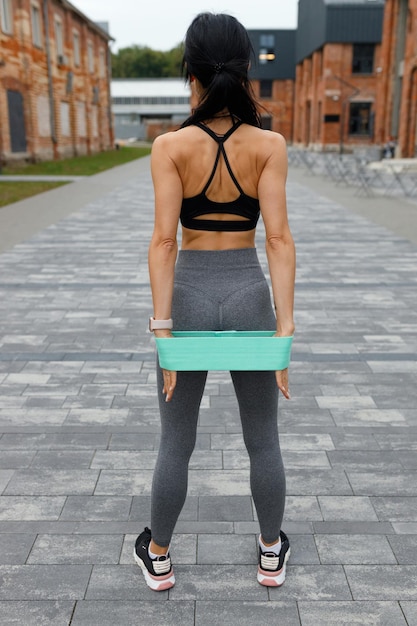 Rear view of a athlete woman who stretches an elastic band