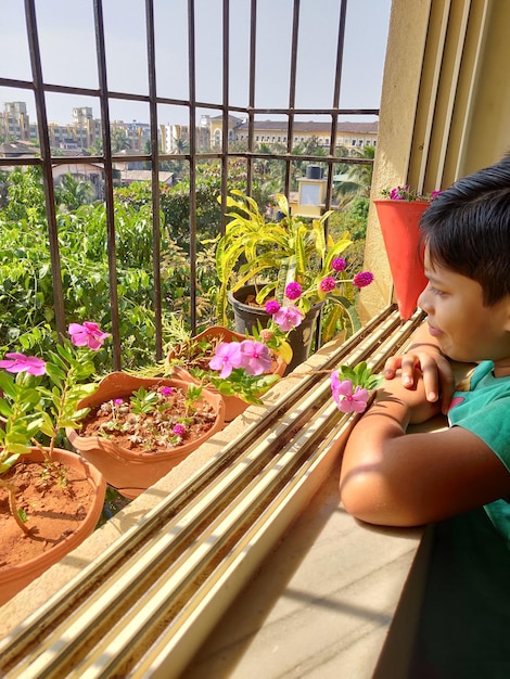 Rear view of a boy with pink flowers against plants