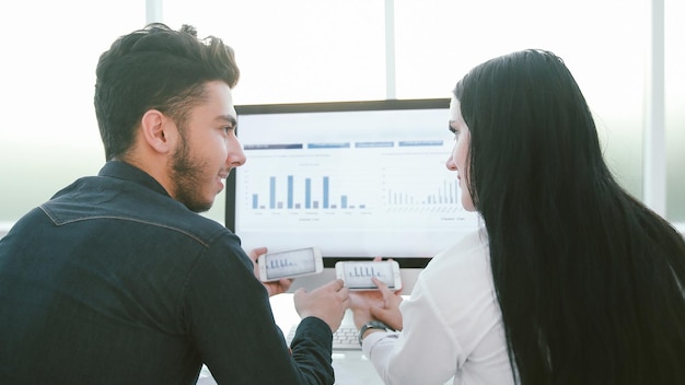 Rear view.business couple discussing financial charts, sitting at your Desk.people and technology