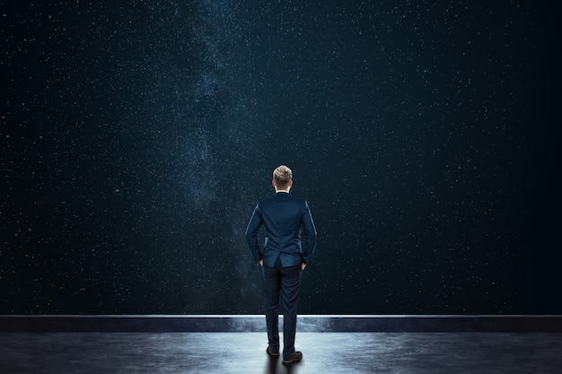 Rear view businessman stands against the background of the starry sky