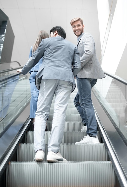 Rear view company employees climbing the escalator business concept