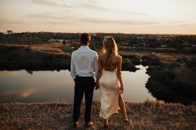 Rear view of a couple cuddling and enjoying sunset together.