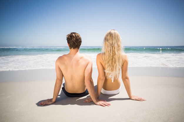 Rear view of couple sitting on the beach