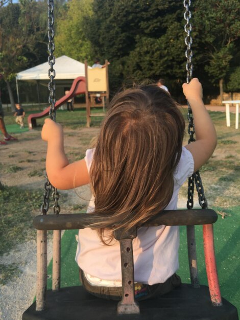 Photo rear view of girl sitting on swing at playground