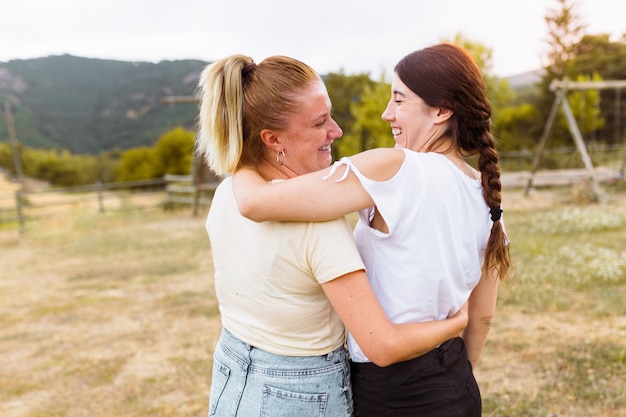 Rear view of girlfriends smiling and hugging each other in the countryside. Best friend, love and friendship concept.