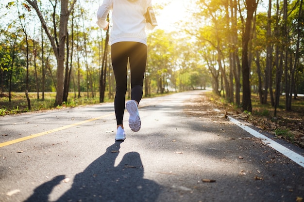 Rear view image of a young asian woman jogging in city park in the morning