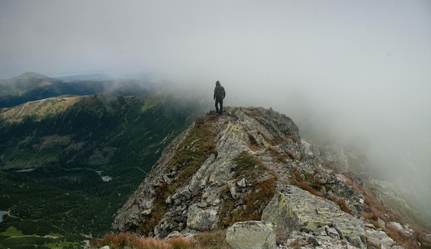 Rear view of male hiker walking on mountain during foggy weather