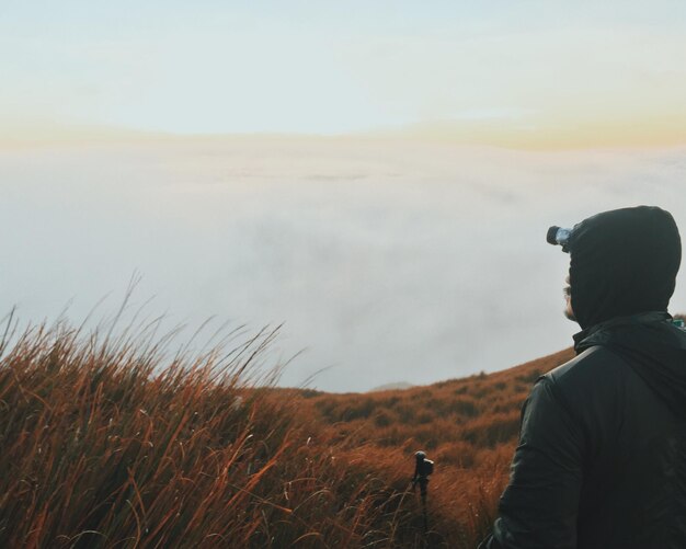 Photo rear view of man hiking on grassy field against sky