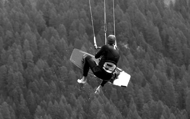 Photo rear view of man jumping while kiteboarding