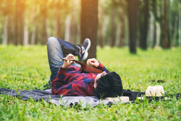 Photo rear view of man playing ukulele while relaxing at forest