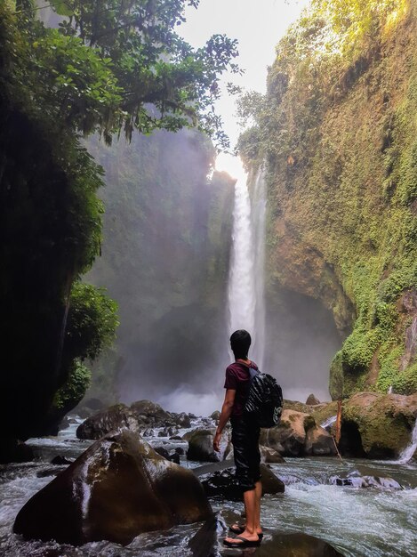 Photo rear view of man standing by waterfall