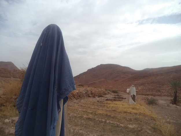 Rear view of man standing on field against sky