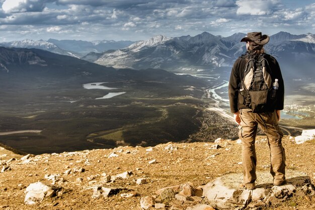 Rear view of man standing on mountain against sky