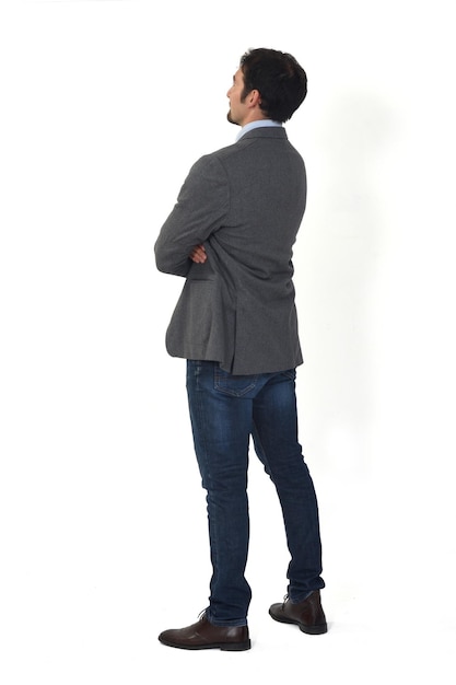 Rear view of a man with blazer and jeans looking up on white background