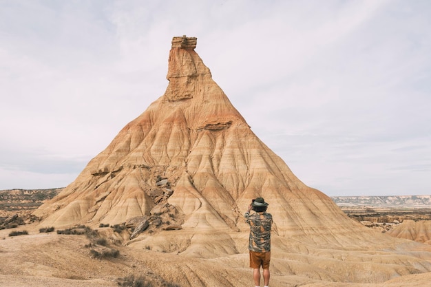 Rear View Of A Man With A Hat Taking A Photo With A Smart Phone In The Bardenas Desert Navarre